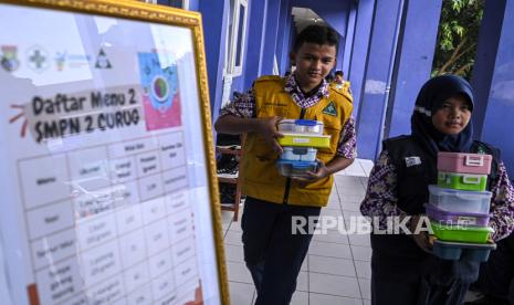 Dua siswa membawa tempat berisi makan saat simulasi program makan siang gratis di SMP Negeri 2 Curug, Kabupaten Tangerang, Banten, Kamis (29/2/2024). 