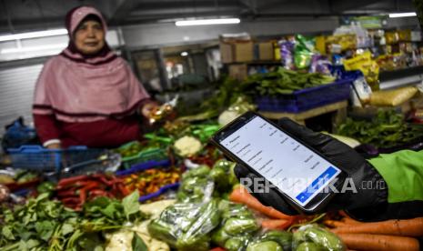 Pengemudi ojek menunjukkan pesanan belanja daring di Pasar Kosambi, Kota Bandung, Ahad (12/4). Layanan jual beli kebutuhan pokok di pasar tradisional secara daring tersebut diharapkan dapat mempermudah masyarakat untuk mendapatkan kebutuhan pokok tanpa harus keluar rumah sekaligus mendukung upaya memutus mata rantai penyabaran virus Corona (Covid-19) melalui jaga jarak fisik dan sosial.