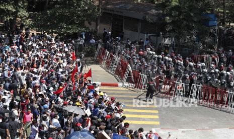  Para pengunjuk rasa meneriakkan slogan-slogan di depan petugas polisi anti huru-hara selama protes menentang kudeta militer, di Yangon, Myanmar,Selasa (9/2). Ribuan orang terus melakukan unjuk rasa di Yangon meskipun ada peringatan keras dari militer setelah beberapa hari protes massal.