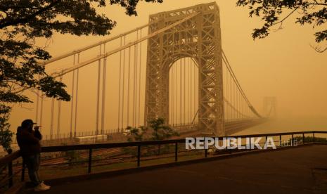 Seorang pria berbicara di ponselnya saat dia melihat kabut di Jembatan George Washington di Fort Lee, N.J., Kamis (8/6/2023)WIB