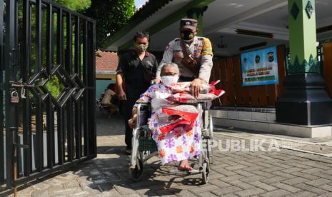 Petugas membantu lansia membawakan beras saat penyaluran bantuan beras PPKM 2021 di Kalurahan Panembahan, Yogyakarta, Jumat (23/7). Angka kematian lansia akibat Covid-19 di Indonesia hingga kini masih cukup tinggi. (ilustrasi)