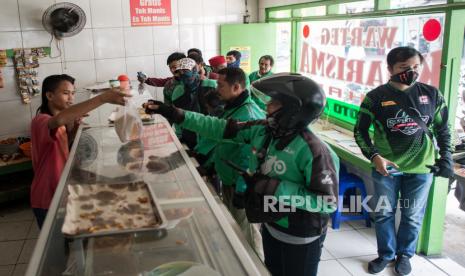 Sejumlah driver ojek online mengantre menunggu layanan makanan gratis di salah satu warteg di kawasan Palmerah, Jakarta  Barat, Selasa (7/4). Ojek online adalah salah satu sektor yang terdampak penerapan Pembatasan Sosial Berskala Besar (PSBB).