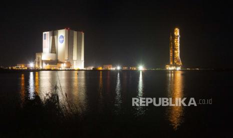 Roket (R) Space Launch System (SLS) NASA dengan pesawat ruang angkasa Orion terlihat di atas peluncur bergerak saat diluncurkan ke Launch Pad 39B di Kennedy Space Center di Merritt Island, Florida, AS, awal 04 November 2022. Artemis 1 misi adalah uji terbang tanpa awak pesawat ruang angkasa Orion dan peluncuran pertama SLS. Artemis adalah misi luar angkasa berkelanjutan yang dijalankan oleh NASA dengan tujuan mendaratkan astronot wanita pertama dan astronot kulit berwarna pertama di Bulan. Ini adalah misi Bulan berawak pertama badan antariksa AS sejak Apollo 17 pada 1972. Peluncuran uji terbang tanpa awak ditargetkan pada 14 November.