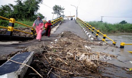 Dua warga melintas di Jembatan Kacangan yang rusak di Desa Bulurejo, Gresik, Jawa Timur, Kamis (9/6/2022). Jembatan sepanjang 90 meter yang menghubungkan antara Desa Bulurejo dengan Desa Gluranploso itu rusak sejak Desember 2021 dan masih menjadi pilihan utama warga setempat untuk menyebrang meskipun membahayakan keselamatan mereka. 