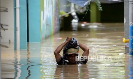 Seorang warga melintasi banjir yang merendam kawasan Kebon Pala, Kampung Melayu, Jatinegara, Jakarta Timur, Senin (27/2/2023). BPBD DKI Jakarta sebut banjir di tujuh kelurahan sebabkan 189 jiwa masih mengungsi.