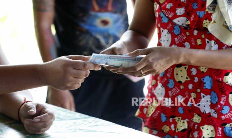  Seorang wanita menerima uang tunai dari otoritas lingkungan di Yangon, Myanmar, 13 November 2020. Junta Myanmar berencana membuat mata uang digital untuk mendukung transaksi pembayaran domestik. 