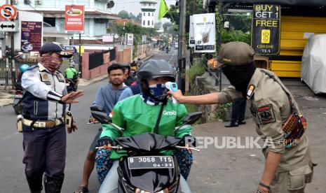 Petugas memeriksa suhu tubuh warga yang melintas di Jalan Bintara Raya, Bekasi, Jawa Barat, Sabtu (4/4/2020). Pemerintah Kota (Pemkot) menjaga ketat pergerakan masyarakat yang akan masuk ke Kota Bekasi dengan memeriksa suhu tubuh di wilayah perbatasan guna mencegah dan memutus penyebaran pandemi COVID-19