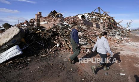 Orang-orang berjalan melewati gedung yang hancur Sabtu, 11 Desember 2021, di Mayfield, Ky. Tornado dan cuaca buruk menyebabkan kerusakan dahsyat di beberapa negara bagian pada hari Jumat, menewaskan banyak orang dalam semalam. Menlu Retno Marsudi mewakili Indonesia mengucap belasungkawa untuk AS.