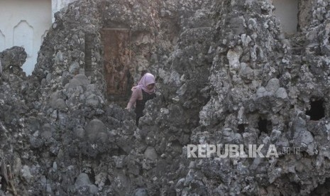 Seorang pengunjung melintas  di lingkungan objek wisata Goa Sunyaragi di Cirebon, Jawa Barat, Ahad (17/6).