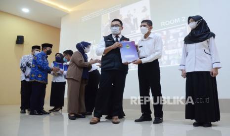 Gubernur Jawa Barat Ridwan Kamil bersama sejumlah pejabat terkait secara simbolis menyerahkan Surat Keputusan (SK) Pegawai Pemerintah dengan Perjanjian Kerja (P3K) tahap satu kepada sejumlah guru saat Pembukaan PPDB Tahun 2022 di Aula SMKN 2 Kota Bandung, Selasa (17/5). Penerimaan Peserta Didik Baru (PPDB) tahap satu akan berlangsung 6-10 Juni 2022 dan tahap dua berlangsung 23-30 Juni 2022. Untuk informasi resmi dan pendaftaran masyarakat bisa melihat di ppdb.disdik.jabarprov.go.id.