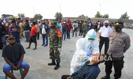 Petugas kesehatan melakukan tes Antigen untuk warga saat turun kapal feri dari Sumenep di Pelabuhan Jangkar, Situbondo, Jawa Timur, Senin (7/6/2021). Petugas gabungan melakukan tes Antigen untuk warga Pulau Madura yang akan masuk Pulau Jawa  menyusul terjadinya lonjakan kasus di Madura dan untuk mengantisipasi penyebaran COVID-19. 