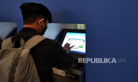 Penumpang menggunakan mesin layanan check in mandiri di Bandara Kualanamu, Sumatera Utara, Jumat (11/2/2023). Pemerintah resmi menurunkan harga tiket pesawat.