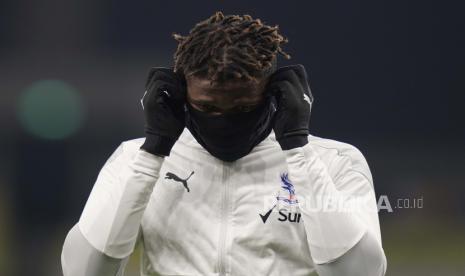 Crystal Palace Wilfried Zaha menyesuaikan masker wajahnya saat dia melakukan pemanasan menjelang pertandingan sepak bola Liga Premier Inggris antara Tottenham Hotspur dan Crystal Palace di Stadion Tottenham Hotspur di London, Minggu, 7 Maret 2021. 