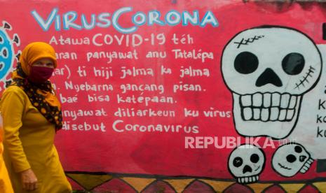 Warga melintasi mural edukasi pencegahan COVID-19 berbahasa Sunda di Pandeglang, Banten. Grafik penambahan kasus harian Covid-19 mulai menunjukkan tren mendatar atau flat dalam dua pekan terakhir di Indonesia.