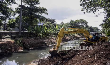 Petugas menggunakan alat berat melakukan pengerukan di pinggiran sungai. 