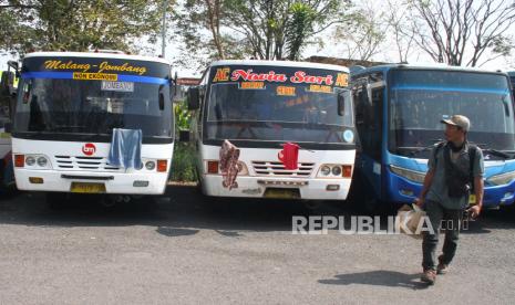 Seorang calon penumpang melintas di depan bus antar kota yang terparkir dan tidak beroperasi di Terminal Landungsari, Malang, Jawa Timur, Senin (11/5/2020). Pengusaha armada bus setempat memilih untuk tidak beroperasi dan meliburkan seluruh awak armada meski Kementerian Perhubungan memberi kelonggaran aktivitas transportasi di tengah pandemi COVID-19