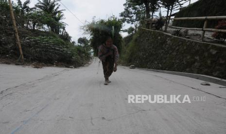 Gunung Merapi Sudah Erupsi Efusif, Apa Itu?. Warga berjalan di jalan desa yang tertutup abu vulkanik Gunung Merapi di Songgo Bumi, Mriyan, Tamansari, Boyolali, Jawa Tengah, Selasa (19/1/2021). Terjadinya awan panas guguran Gunung Merapi pada Selasa (19/1) pukul 02.27 WIB dengan jarak luncur 1800 meter dan tinggi kolom 500 meter di atas puncak, membuat sebagian wilayah di daerah kaki Gunung Merapi Kabupaten Boyolali dan Kabupaten Klaten terkena hujan abu vulkanik.