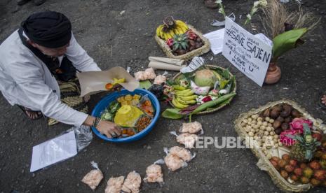 Seorang budayawan mengambil nasi tumpeng saat aksi Save Sesajen Damai untuk Tradisi Nusantara di depan Monumen Perjuangan Rakyat, Bandung, Jawa Barat, Ahad (16/1/2022). Aksi tersebut dilakukan sebagai respon damai terhadap peristiwa perusakan sesajen di Gunung Semeru yang dianggap menciderai salah satu simbol kebhinekaan dan tradisi rasa syukur masyarakat adat nusantara yang sudah ada sejak dulu. 