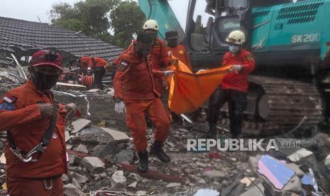  Tim penyelamat mengambil jenazah seorang anak dari reruntuhan bangunan yang rusak akibat gempa bumi di Mamuju, Sulawesi Barat,  Jumat (15/1/2021). 