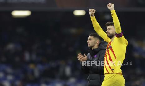 Pemain Barcelona Gerard Pique, kanan, memberi isyarat selama pertandingan sepak bola Liga Europa antara Napoli dan Barcelona di stadion Diego Armando Maradona, di Naples, Italia, Kamis, 24 Februari 2022.