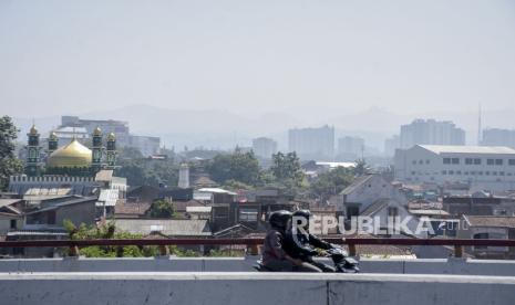 Pengendara melintas dengan latar belakang suasana Kota Bandung yang diselimuti kabut tipis terlihat dari Cihampelas, Kota Bandung, Jawa Barat, Senin (21/8/2023). Berdasarkan data dari Dinas Lingkungan Hidup (DLH) Kota Bandung dalam satu minggu terakhir, Indeks Standar Polusi Udara (ISPU) Kota Bandung berada pada angka 96 dan terendah pada angka 67 untuk parameter PM2,5 atau dalam kategori sedang. Untuk itu DLH Kota Bandung mengimbau warga untuk menggunakan masker di luar ruang, melakukan uji emisi kendaraan serta melakukan penanaman pohon.