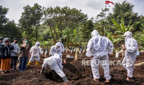 Petugas pemikul jenazah mengenakan alat pelindung diri (APD) memakamkan jenazah dengan protokol Covid-19 di TPU Kihafit, Leuwigajah, Kota Cimahi, Ahad (22/8). Kasus meninggal harian akibat Covid-19 terus mengalami penurunan. Pada Ahad (26/9), Satuan Tugas Penanganan Covid-19 melaporkan jumlah kasus meninggal harian bahkan berada di bawah 100 kasus, yakni sebanyak 86 orang.