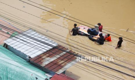 Warga menaiki rakit untuk melintasi jalan yang terendam banjir di Jalan Dayeuhkolot, Kabupaten Bandung, Jumat (12/1/2024). 