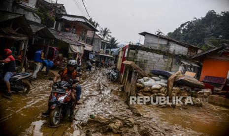 Sejumlah warga melintasi jalan yang tertutup lumpur di Desa Purasari, Leuwiliang, Kabupaten Bogor, Jawa Barat. PT Bank Syariah Indonesia Tbk (BSI) dan Lembaga Amil Zakat Nasional Bangun Sejahtera Mitra Umat (Laznas BSM Umat) menyalurkan bantuan kepada warga yang terdampak banjir dan longsor di Bogor, Jawa Barat. Banjir bandang dan tanah longsor melanda Desa Cibunian, Kecamatan Pamijahan, Kabupaten Bogor dan Desa Purasari, Kec. Leuwiliang karena tingginya intensitas hujan dan luapan air sungai.