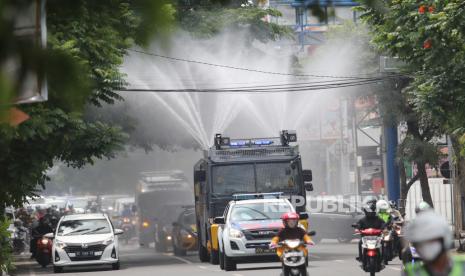 Petugas kepolisian menyemprotkan cairan disinfektan