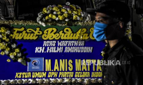 Petugas keamanan berdiri di depan karangan bunga duka cita almarhum KH Hilmi Aminuddin di rumah duka di Jalan Pagermaneuh, Lembang, Kabupaten Bandung Barat, Selas (30/6). Salah satu pendiri yang juga mantan Ketua Majelis Syuro Partai Keadilan Sejahtera (PKS) Hilmi Aminuddin meninggal dunia pada pukul 14.24 WIB pada usia 72 tahun, Almarhum dimakamkan di pemakaman keluarga dan sesuai dengan protokol penanganan Covid-19. Foto: Abdan Syakura/Republika