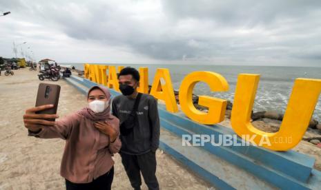 Pengunjung berfoto di pantai wisata Jawa-Hagu (JAGU), Kota Lhokseumawe, Aceh, Selasa (7/12). Direktur Utama PT Aviasi Pariwisata Indonesia (Persero), Aviata, atau InJourney Dony Oskaria mengatakan pemulihan pariwisata nasional pada masa adaptasi kebiasaan baru merupakan salah satu fokus Holding BUMN Aviasi dan Pariwisata. 