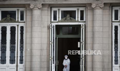 Seorang penjaga dengan alat pelindung berpatroli di pintu masuk Colon Theatre di Buenos Aires, Argentina, Rabu, 17 Februari 2021, di tengah pandemi virus corona baru.