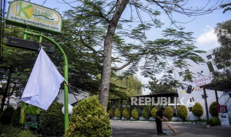 Pekerja beraktivitas di dekat bendera putih yang dipasang di salah satu restoran di Jalan Cikutra, Kota Bandung, Kamis (29/7). Sejumlah pengusaha kafe dan restoran di Kota Bandung menggelar aksi pengibaran bendera putih sebagai bentuk protes kebijakan pemerintah yang dinilai tidak mempedulikan nasib para pelaku usaha kafe dan restoran yang terdampak penerapan Pemberlakuan Pembatasan Kegiatan Masyarakat (PPKM). Foto: Republika/Abdan Syakura