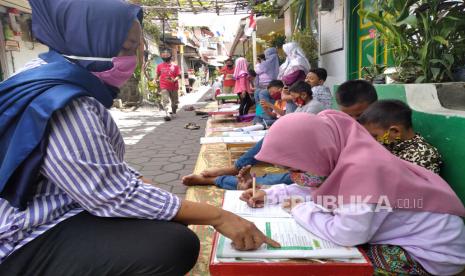 Anak-anak siswa SD belajar bersama jalan kampung. Layanan Internet Masyarakat (LIMas) memberikan akses internet gratis untuk anak-anak untuk mempermudah kegiatan belajar secara daring.