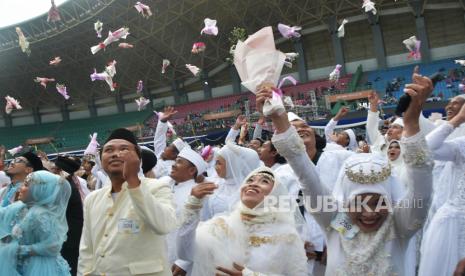 Sejumlah pengantin melempar bunga usai mengikuti nikah massal juara di Stadion Patriot Chandrabhaga, Bekasi, Jawa Barat, Minggu (14/5/2023). Pemerintah Provinsi Jawa Barat memfasilitasi kegiatan nikah massal gratis yang sah secara agama dan hukum untuk 300 calon pengantin. 