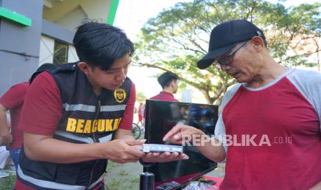 Petugas Bea Cukai menunjukan cara membedakan pita cukai rokok asli dan palsu kepada seorang pengunjung pada warga (ilustrasi) 