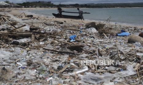 Nelayan mengangkut sampan di dekat tumpukan sampah di Pantai Kedonganan, Badung, Bali.