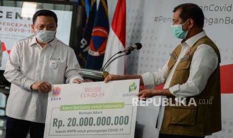 Presiden Direktur PT Adaro Garibaldi Thohir (kiri) bersama Ketua Gugus Tugas Penanganan COVID-19 Doni Monardo (kanan) menyerahkan bantuan kepada BNPB di Gedung Graha BNPB, Jakarta, Senin (23/3). 