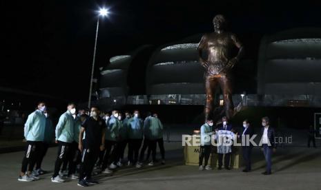 Lionel Messi (tengah) dan pemain lain dari tim nasional Argentina mengambil bagian dalam penghormatan kepada Diego Armando Maradona di samping patung untuk menghormati mendiang pemain Argentina, di luar Stadion Unico di Santiago del Estero, Argentina, 3 Juni 2021.