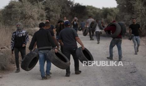 Demonstran Palestina memegang ban selama demonstrasi menentang pos terdepan pemukiman Yahudi Tepi Barat Eviatar yang dengan cepat didirikan bulan lalu, di desa Palestina Beita, dekat kota Nablus, Tepi Barat, Minggu, 27 Juni 2021. 