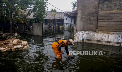 Petugas Satpol PP membersihkan sampah saat terjadi banjir di kawasan Duren Sawit, Jakarta, Selasa (15/3/2022). Menurut warga, banjir setinggi 40 cm hingga 80 cm yang telah merendam pemukiman hingga sepekan tersebut diakibatkan saluran air dari Waduk Haji Dogol ke Kanal Banjir Timur (KBT) yang tersumbat tanah. Republika/Putra M. Akbar