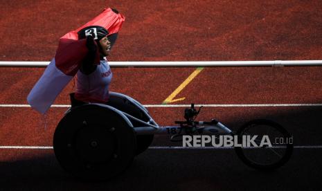 Atlet balap kursi roda Indonesia Maria Goreti Samiyati berselebrasi dengan membawa bendera usai finis pertama pada final 400 meter putri T54 ASEAN Para Games 2022 di Stadion Manahan, Solo, Jawa Tengah, Kamis (4/8/2022). Maria Goreti Samiyati meraih medali emas dengan catatan waktu 1 menit 2,77 detik, sementara rekannya Nina Gusmita memperoleh medali perunggu dengan cacatan waktu 1 menit 06 detik. 