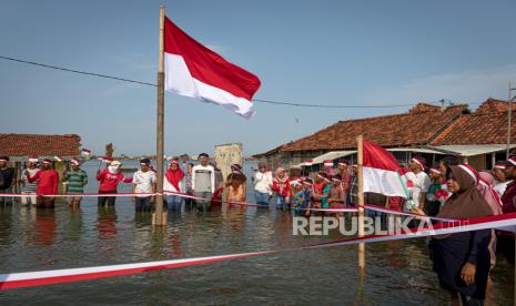 Sejumlah warga mengikuti upacara bendera di perkampungan mereka yang terendam banjir rob (limpasan air laut ke daratan) di Dukuh Timbulsloko, Sayung, Demak, Jawa Tengah, Rabu (17/8/2022).(Ilustrasi)