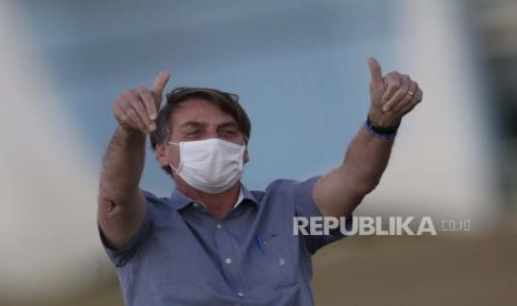 Presiden Brazil Jair Bolsonaro yang terinfeksi COVID-19, mengenakan masker pelindung saat ia melambai kepada pendukungnya selama upacara retret bendera Brasil di luar kediaman resminya Istana Alvorada, di Brasilia, Brasil, Jumat, 17 Juli 2020.