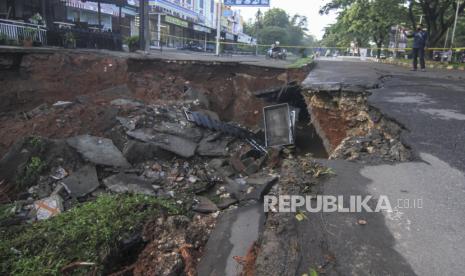 Warga memfoto jalan yang longsor di Jalan Raya Boulevard, GDC, Depok, Jawa Barat, Selasa (13/4/2021).Longsor yang terjadi pada Senin (12/4) pukul 21.00 WIB tersebut akibat intensitas hujan yang tinggi  dan menyebabkan sebagain jalan amblas dengan kedalaman dan lebar kurang lebih 5 meter. 