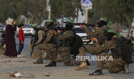  Militan bertopeng dari Brigade Izzedine al-Qassam, sayap militer Hamas, mengambil posisi untuk mengamankan rekan-rekan mereka yang berbaris di sepanjang jalan utama kamp pengungsi Nusseirat, Jalur Gaza tengah, Kamis, 28 Oktober 2021. Komunitas internasional telah mengirimkan miliaran dolar bantuan ke Jalur Gaza dalam beberapa tahun terakhir. 