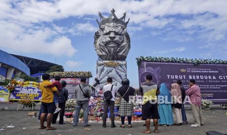 Orang-orang berdoa di dekat patung singa, maskot Arema FC, di luar Stadion Kanjuruhan di mana penyerbuan sepak bola menewaskan lebih dari 100 orang pada hari Sabtu, di Malang, Jawa Timur, Indonesia, Selasa, 4 Oktober 2022. Kementerian PUPR membenahi Stadion Kanjuruhan untuk meningkatkan keselamatan suporter