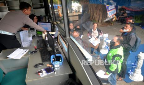 Petugas melayani warga yang membayar pajak kendaraan lima tahunan di Layanan Mobil Keliling Samsat Mobile Lima Tahunan (Samoli) di Pakualaman, Yogyakarta, Kamis (13/7/2023). Ditlantas Polda DIY membuat terobosan baru perpanjangan STNK lima tahunan dan pembayaran pajak kendaraan bermotor atau mobil melalui layanan keliling Samoli. Layanan Samoli ini untuk mempermudah masyarakat melakukan pembayaran pajak lima tahun tanpa harus ke kantor  Samsat. Layanan baru tersedia satu mobil dan berganti tempat setiap hari mulai dari Purawisata, Lapangan Minggiran, XT Square, Pura Pakualaman, dan Kantor LPP.