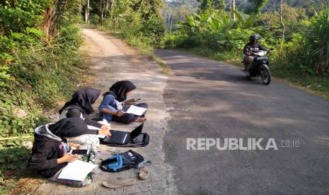 Mahasiswa Universitas Muhammadiyah Magelang (UMM) Teara Noviani (tengah) bersama sepupunya siswi SMK Fitri (kiri) dan adiknya pelajar SMP Salma belajar menggunakan sistem daring di tepi jalan Desa Kenalan, Magelang, Jawa Tengah, Selasa (21/7). Susahnya sinyal menjadi alasan mengapa mereka belajar di tepi jalan desa. Menurut Teara, di titik itu sinyal paling kuat dan memungkinkan untuk mengikuti kuliah secara daring. Dia mengikuti kuliah dari tempat tersebut sejak pandemi Covid-19 merebak, atau sudah hampir empat bulan lamanya.