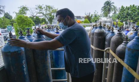 Pekerja mengangkut tabung oksigen medis untuk didistribusikan. ilustrasi